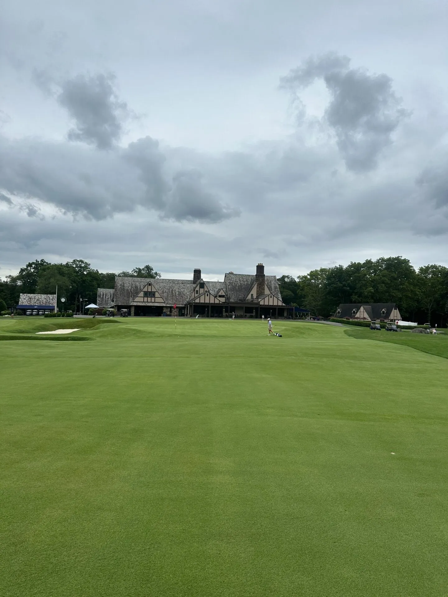 Looking up the fairway toward the Tudor clubhouse at North Jersey, bunkers guarding the green with a lone golfer on the putting surface