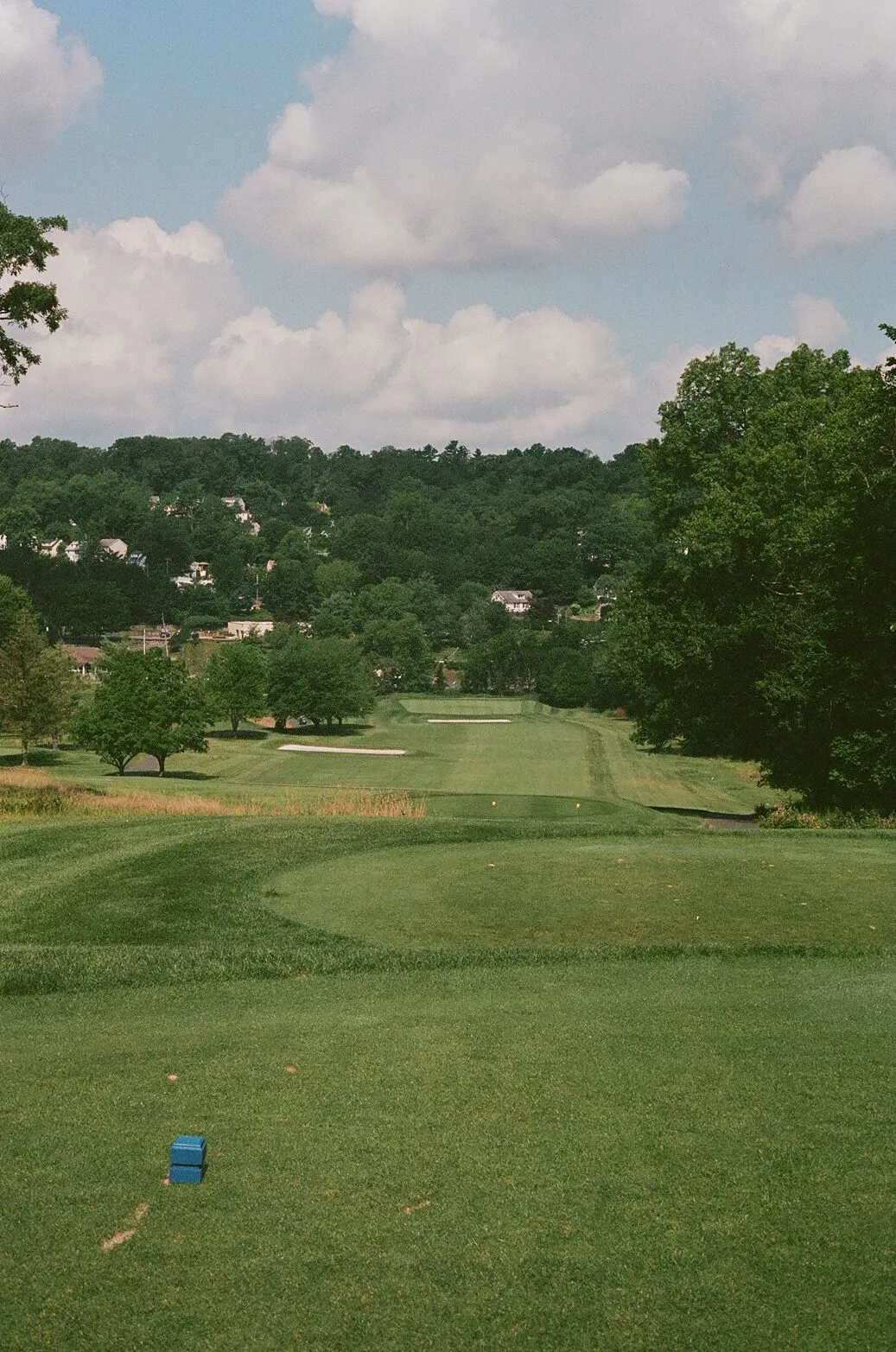From an elevated tee at Francis A. Byrne, looking down a long fairway lined with bunkers, the town of West Orange climbing the hillside beyond