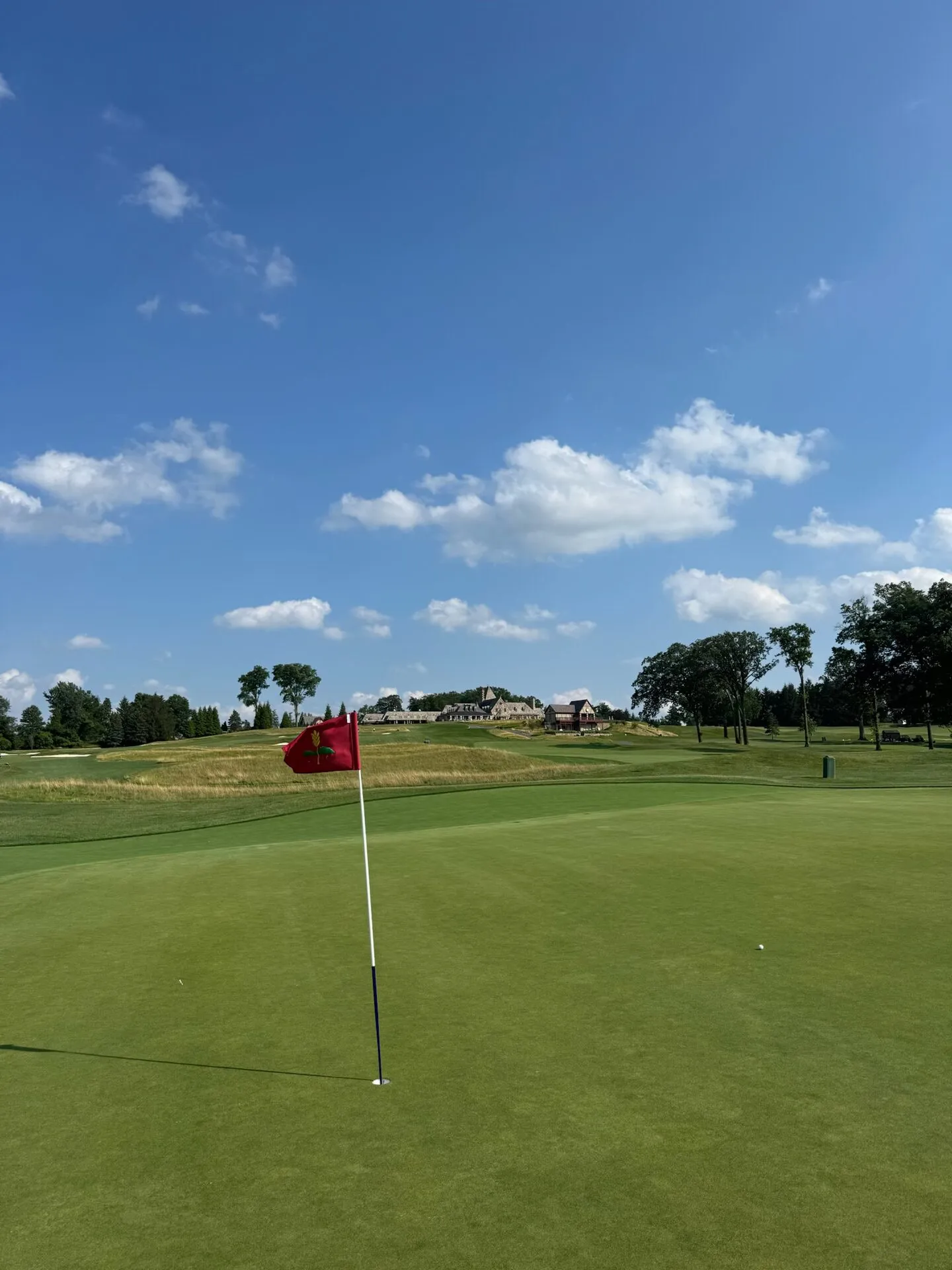 The red Mountain Ridge flag on the green with the clubhouse visible through golden fescue on the distant ridge
