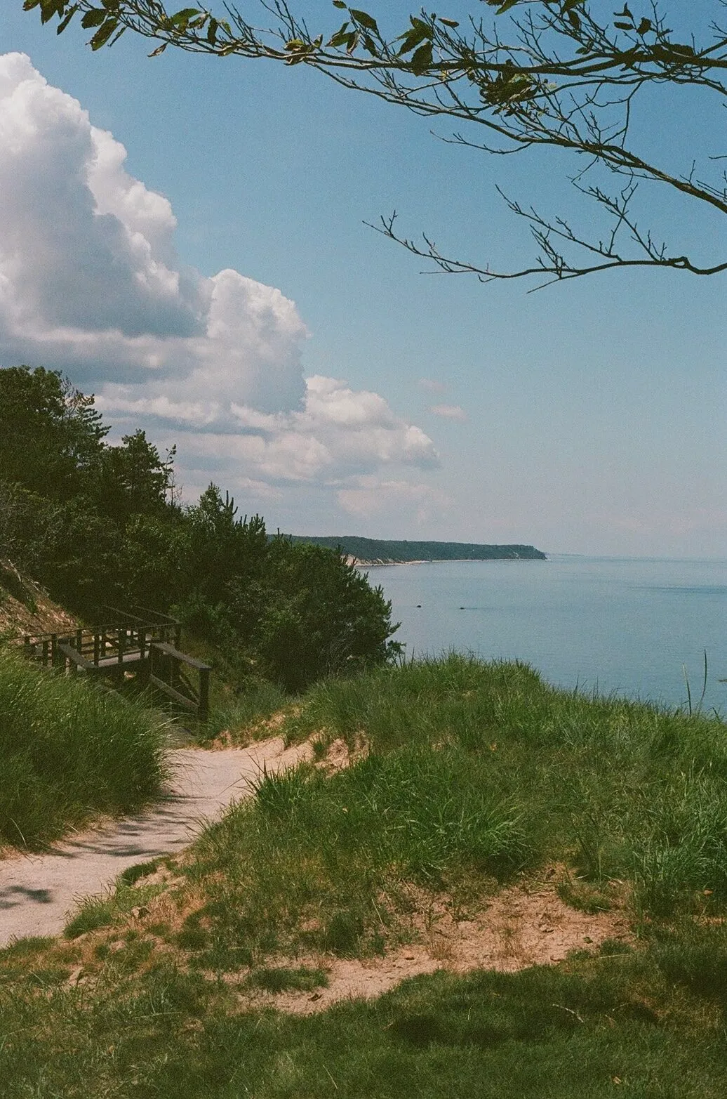 The red and white checkered flag at Friar's Head standing on a green with sand dunes and the blue waters of Long Island Sound behind it, shot on 35mm film
