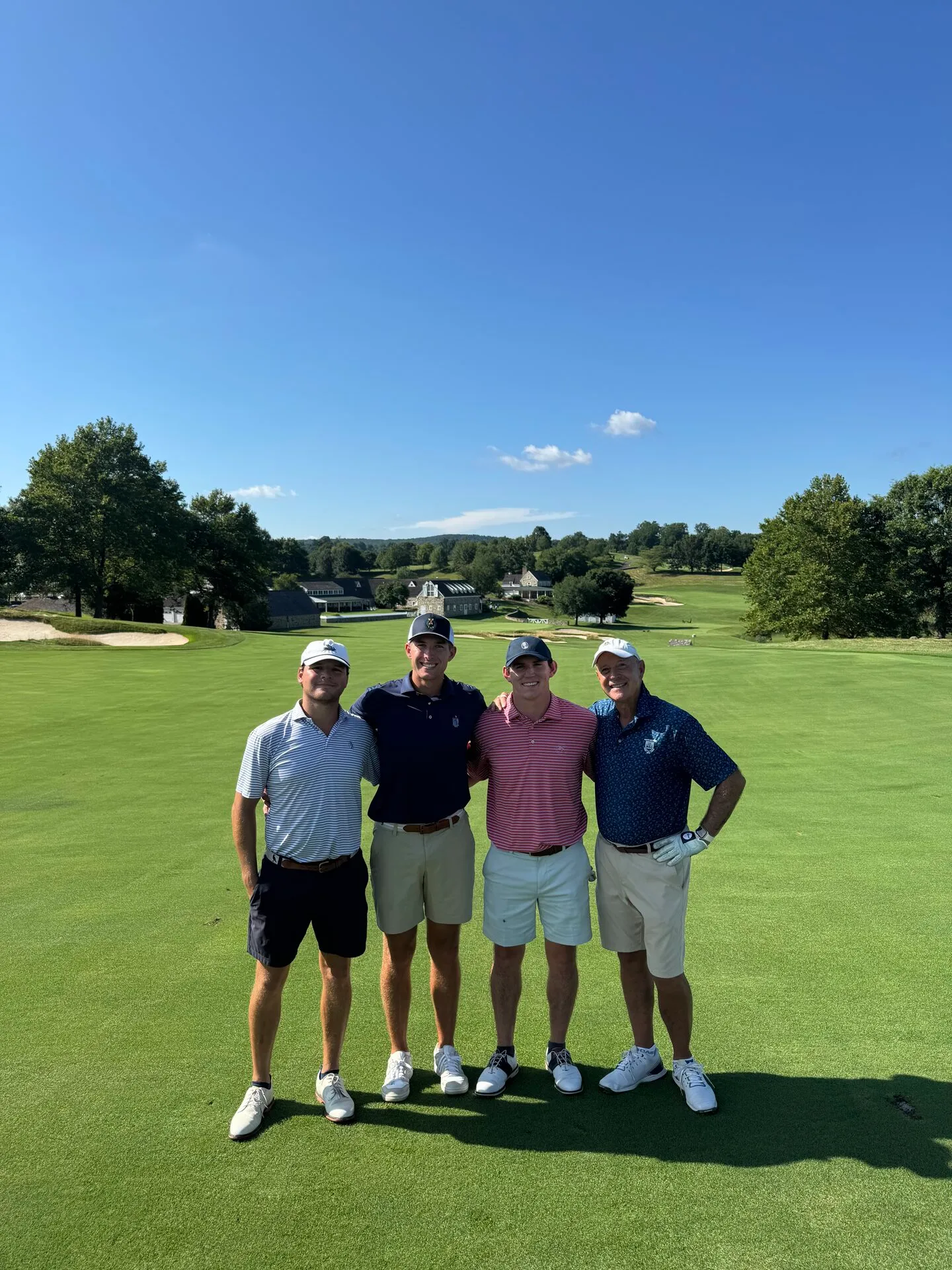 The foursome on the fairway at Stonewall, the stone clubhouse and Pennsylvania countryside stretching out behind them
