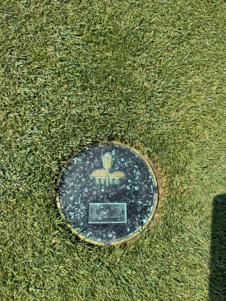 Bronze tee marker embedded in the turf at Mountain Ridge showing the club crest and 1912 founding date