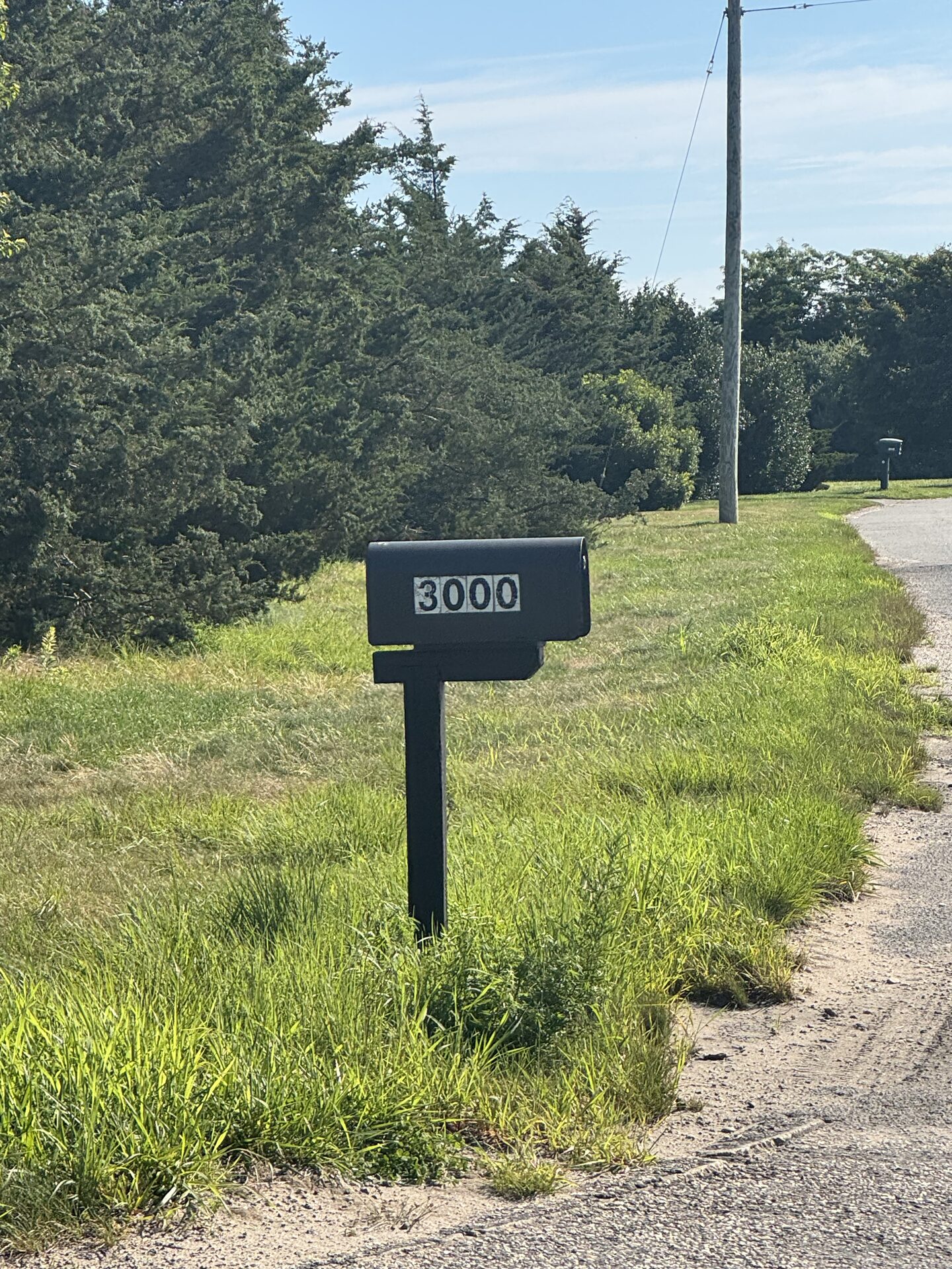 A plain black mailbox numbered 3000 on a quiet country road in Baiting Hollow, Long Island, the unmarked entrance to Friar's Head Golf Links