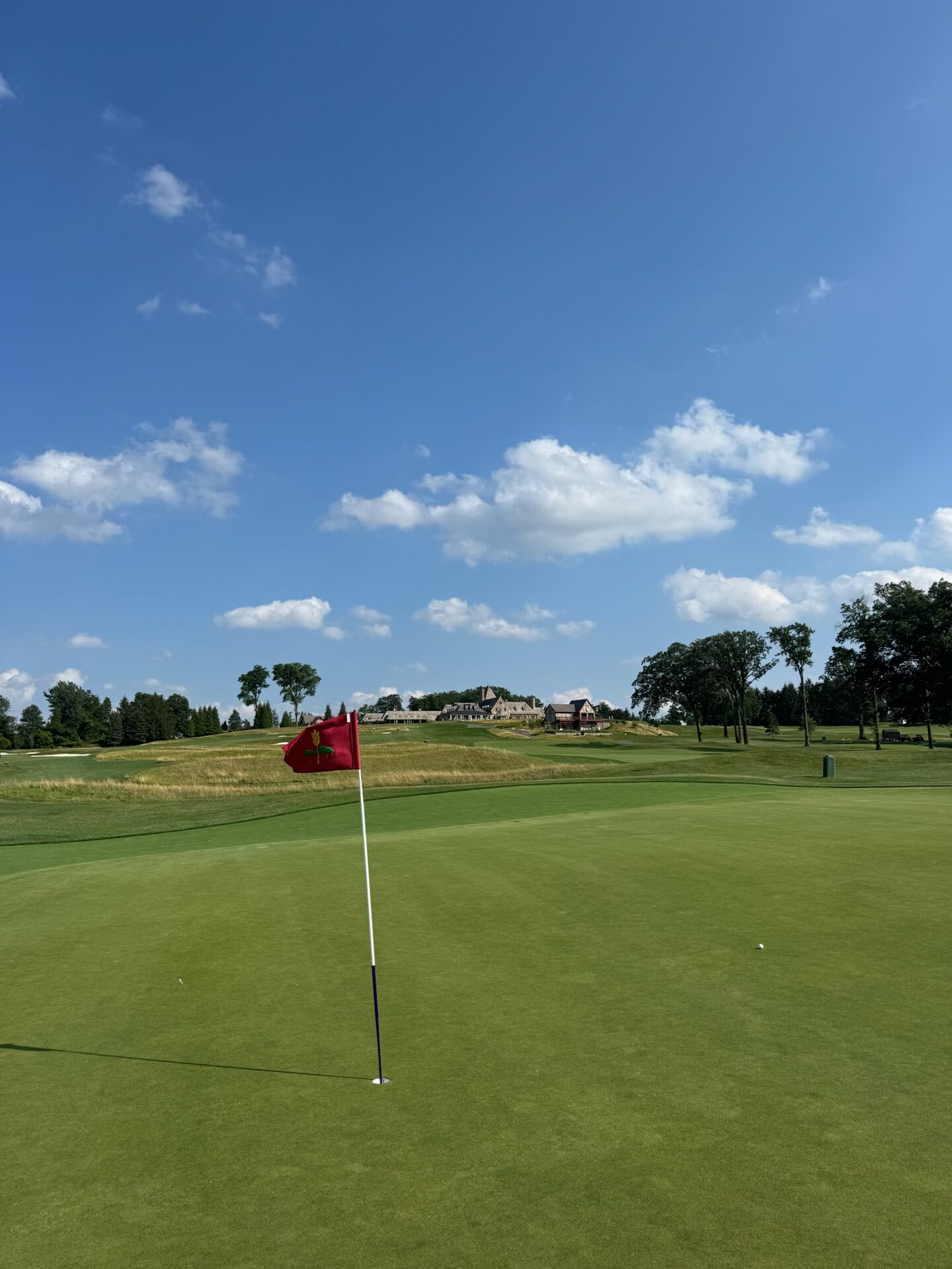 The red Mountain Ridge flag on the green with the clubhouse visible through golden fescue on the distant ridge