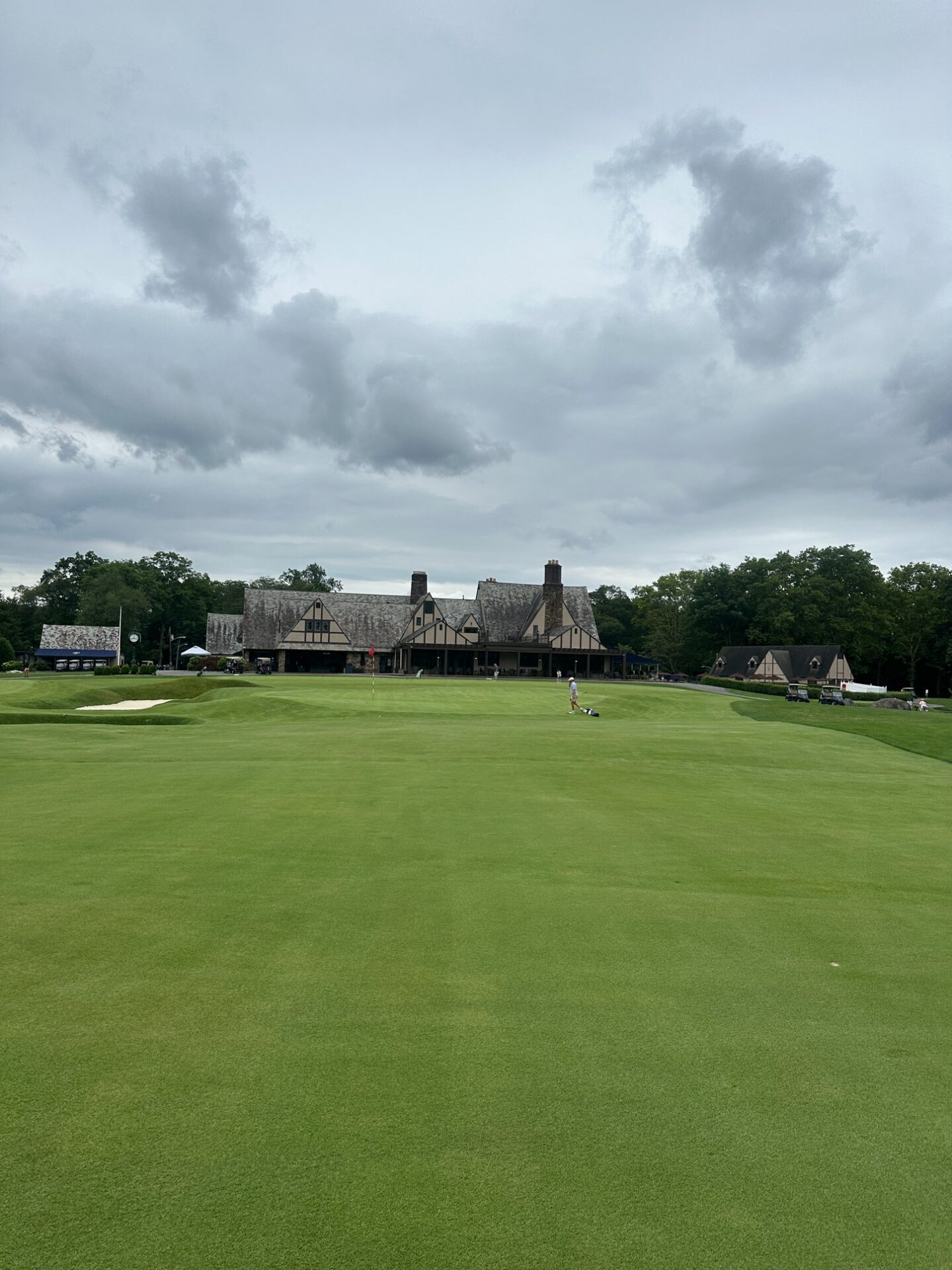 Looking up the fairway toward the Tudor clubhouse at North Jersey, bunkers guarding the green with a lone golfer on the putting surface
