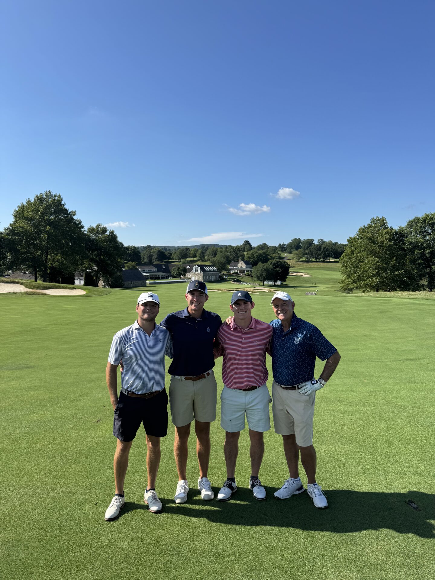 The foursome on the fairway at Stonewall, the stone clubhouse and Pennsylvania countryside stretching out behind them
